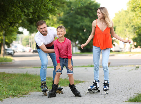 Young happy family roller skating on city street