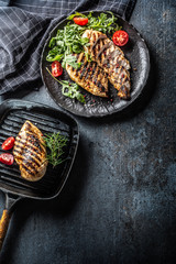 Chicken breast grilled with spices peper salt tomatoes rosemary and arugula - Top of view