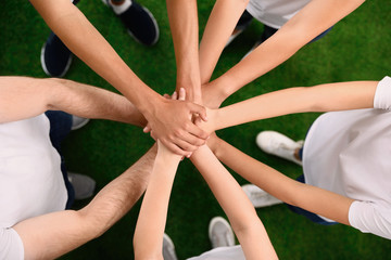 Group of volunteers joining hands together outdoors, top view
