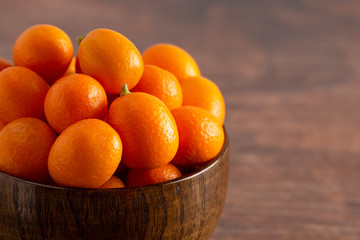 Bowl of Fresh Kumquats on a Rustic Wooden Table