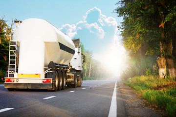 Arriving white truck on the road in a rural landscape at sunset