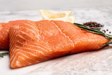 Marble board with tasty salmon fillet on table, closeup