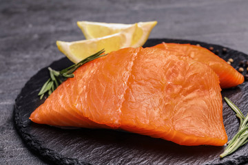 Slate plate with salmon fillet on grey table, closeup
