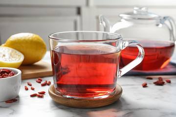 Healthy goji tea with lemon in glass cup on marble table