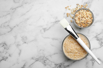 Handmade face mask made of oatmeal on white marble table, flat lay. Space for text