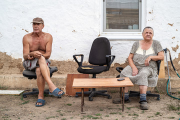 Elderly married couple in the yard of a rural house. Photo taken in Russia, in the countryside