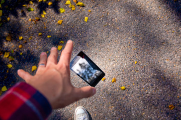 Man dropping his smartphone ad trying to reach it. Phone screen is cracked and needs repairing....