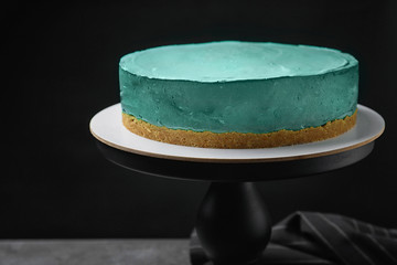 Delicious homemade spirulina cheesecake on table against black background