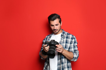 Young photographer with professional camera on red background