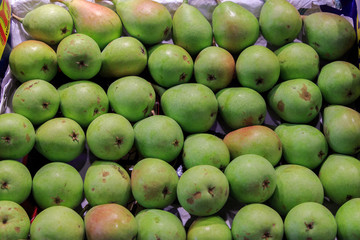 Group of fresh green pears ordered in a box put up for sale at the Boqueria market. Food concept