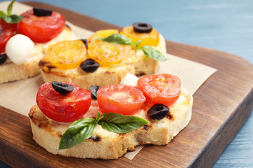 Delicious tomato bruschettas on wooden board, closeup