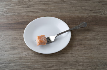 Morsel of salmon on a white plate with a fork