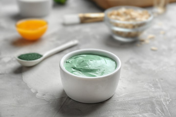 Bowl of spirulina facial mask on grey table
