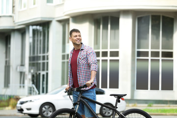 Fototapeta na wymiar Handsome man with modern bicycle on city street