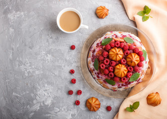 Homemade jelly cake with milk, cookies and raspberry on a gray concrete  background with cup of coffee and orange textile, top view.