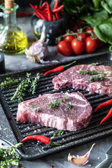 Raw fresh meat. Steak for two with ingredients in a grill pan, with spices, vegetables and herbs