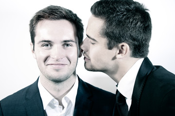 Portrait of handsome gay couple with one smiling at camera as the other is about to kiss his cheek