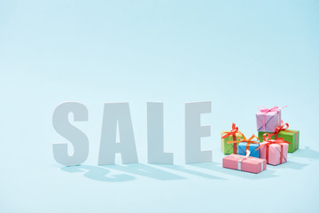 Fototapeta premium white sale lettering and festive gift boxes on blue background