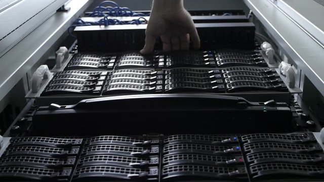 In Fully Working Data Center IT Engineer Installs Hard Drive into Server Rack.
