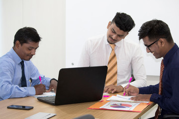 Obraz premium Three business colleagues writing notes during a meeting in conference room