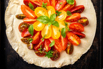 Summer cake with cherry tomatoes, brie cheese and basil. Baking dough with vegetables, greens.