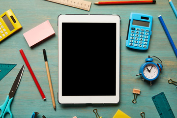 top view of digital tablet with blank screen near school supplies at wooden table