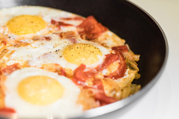 Fried eggs with onions, tomato and pepper, cooking in a pan, breakfast, healthy lifestyle