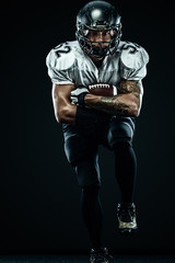 Fototapeta na wymiar American football sportsman player in helmet isolated run in action on black background. Sport and motivation wallpaper. Team sports,