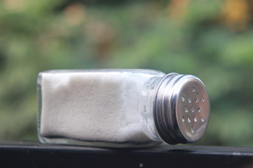 salt from small shaker at garden, green background