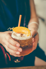 The glass of peach ice tea on wooden table in coffee shop.iced tea cocktail, cold drink or lemonade with fruits.Vintage tone.