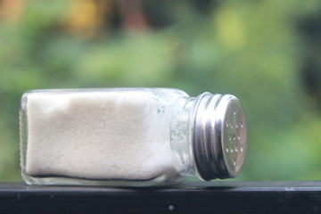 salt from small shaker at garden, green background