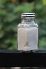 salt from small shaker at garden, green background