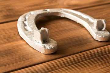 Silver horseshoe on a wooden table. An old horseshoe. Close up.