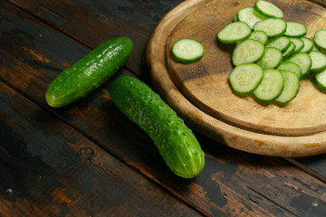 Whole and sliced cucumber on a wooden cutting board. Cucumber slices.