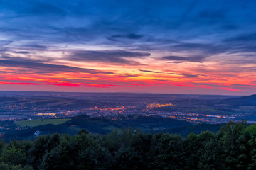 The setting sunset over the town of Valasske Mezirici as the city and its surroundings public light up slowly multi colored dark clouds and sun hiding below horizon.