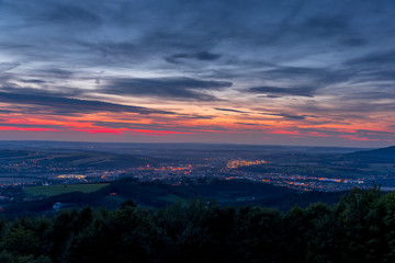 The setting sunset over the town of Valasske Mezirici as the city and its surroundings public light up slowly multi colored dark clouds and sun hiding below horizon.
