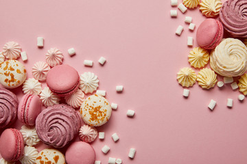 Smashed delicious sweet meringues, macaroons and small marshmallows pieces on pink background - Powered by Adobe