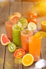 Flasses of various juice with ingredients on wooden table