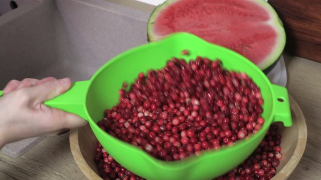 Woman holding and shaking green bowl with cranberries