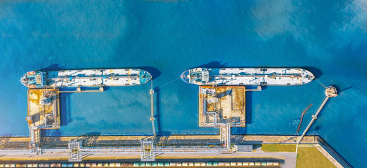 Aerial top view wide panorama of the oil terminal and two moored tankers with liquid fuel loaded on...