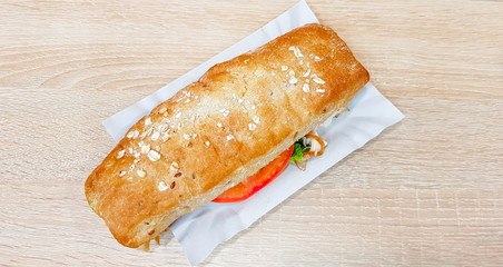 Ciabatta sandwich with lettuce, chicken and cheese on a wooden table