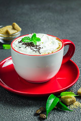 Coffee latte with mint in red cup on dark background. Selective focus, space for text.