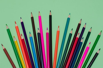 Many colored pencils lie on a green background. Copy spase. The concept of back to school, the educational process, study at school, drawing