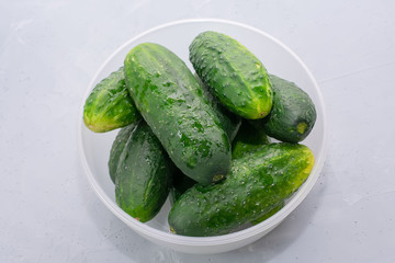 Bowl with green cucumbers on a light background