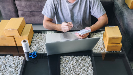 Small business parcel for shipment to client at home, Young entrepreneur SME freelance man working with note packaging sort box delivery online market on purchase order and preparing package product
