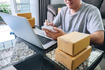Small business parcel for shipment to client at home, Young entrepreneur SME freelance man working with note packaging sort box delivery online market on purchase order and preparing package product