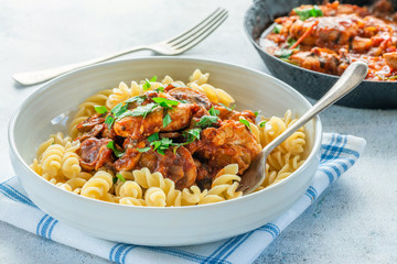 Smoky chicken and mushrooms with tomto sauce and pasta in a bowl