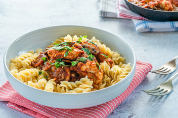Smoky chicken and mushrooms with tomto sauce and pasta in a bowl