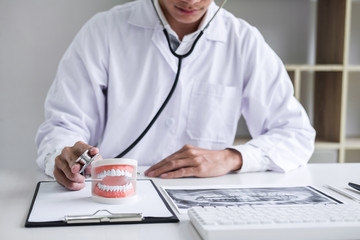 Male doctor or dentist checking teeth disease in dental model and equipment used in the treatment of dental and dentistry at workplace