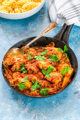 Smoky chicken and mushrooms with tomto sauce and pasta in a frying pan